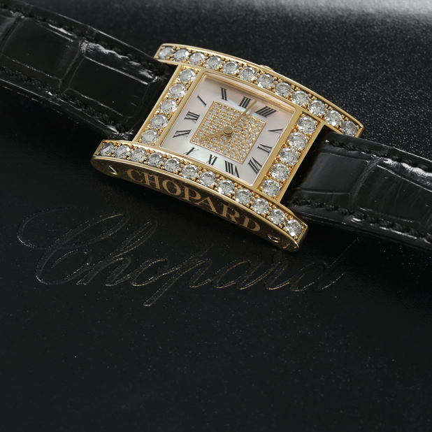 chopard-watch-on-black-surface-with-logo-in-background